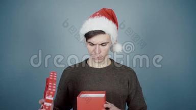 戴着圣诞帽的年轻人打开了一个礼品盒，里面有一个惊喜，看到了有趣的眼镜